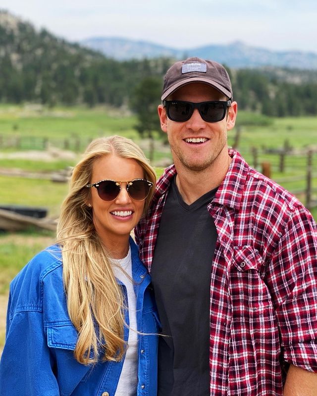 Lauren Tannehill in a blue shirt and her husband in a check shirt smiling in goggles. 